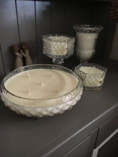 candles are sitting on a table next to some glass dishes