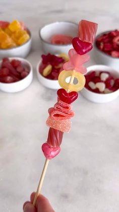 a person is holding a candy lollipop skewer with gummy bears on it