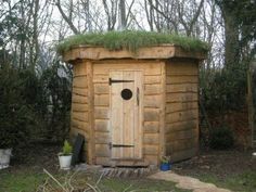 a small wooden outhouse with grass on the roof