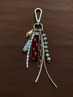 a key chain with beads and charms hanging from it's side on a brown background