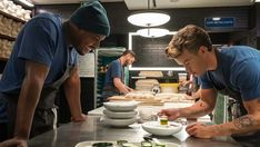 two men are preparing food in a kitchen