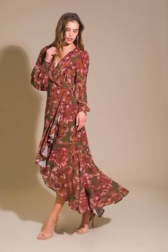 a woman in a floral print dress poses for the camera with her hand on her hip