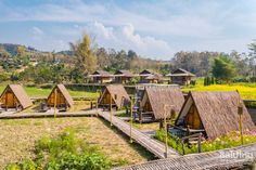 small huts with thatched roofs are in the middle of a field