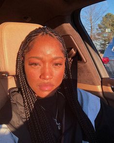 a woman sitting in the back seat of a car with her hair braided up