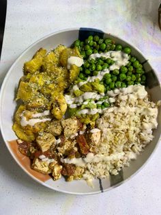 a white plate topped with rice, peas and other foods on top of a table