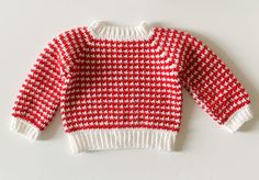 a red and white knitted sweater sitting on top of a table