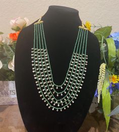 Elevate your style with this exquisite multi-layered necklace featuring emerald beads and Polki stone accents. The necklace showcases five elegant layers of green emerald beads, each adorned with sparkling Polki stones, creating a cascading effect that is both glamorous and sophisticated. This gold replica necklace is perfect for special occasions or adding a touch of elegance to any outfit. This beautiful necklace is a statement piece that will turn heads and add a touch of luxury to your jewelry collection. Don't miss out on owning this stunning accessory! Elegant Green Beaded Kundan Necklace, Green Beaded Chain For Wedding, Green Beaded Bridal Necklace With Round Beads, Green Kundan Necklace With Round Gemstone Beads, Elegant Green Kundan Necklace With Round Beads, Green Kundan Necklace With Faceted Beads As Gift, Green Oval Beaded Chain Jewelry, Green Necklaces With Oval Beaded Chain, Green Gemstone Beads For Wedding