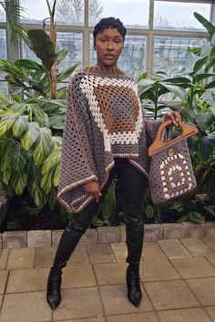 a woman is holding two purses and posing for the camera in front of some plants