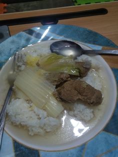 a white plate topped with rice and meat on top of a blue tile countertop