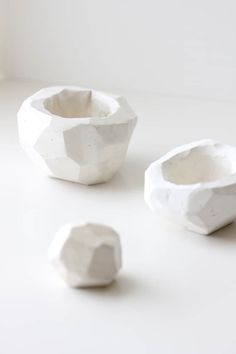 three white ceramic bowls sitting next to each other on top of a table with one bowl in the middle