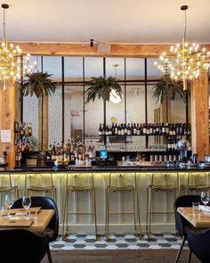 a bar with lots of bottles and glasses on top of it next to two tables