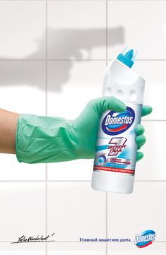 a hand in green gloves holding a bottle of cleaner's detergent on a tiled wall