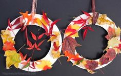 two wreaths made out of paper plates with autumn leaves hanging from the top and bottom