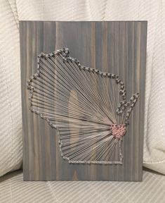 a string art piece with the shape of indiana in grey and pink on a white couch