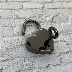 a heart shaped lock with a key hanging from it's side on a white surface