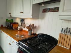 a black stove top oven sitting inside of a kitchen next to white cabinets and wooden counter tops