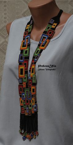 a woman wearing a white shirt and multicolored beaded necklace on top of a mannequin