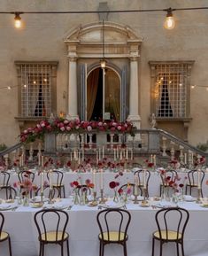 the tables are set with candles, flowers and vases in front of an old building