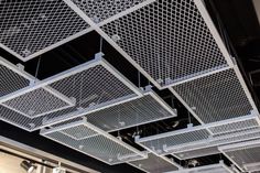 the ceiling is made up of metal squares and grids that are suspended from the ceiling