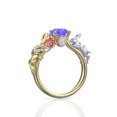 a gold ring with three different colored stones on the top and two smaller flowers on the bottom