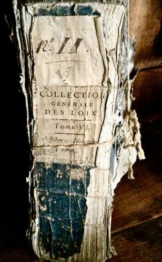 an old book with torn pages sitting on top of a wooden table