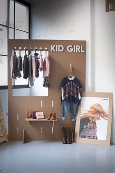 a kid's room with clothes hanging on the wall, and a sign that says kid girl