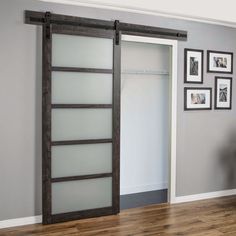 an open sliding door in a room with pictures on the wall and hardwood flooring