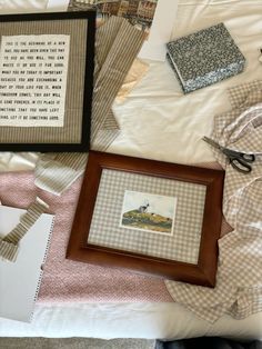 a bed topped with pictures and other items next to a framed painting on top of it