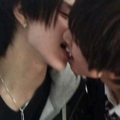 two young men are kissing each other while wearing necklaces