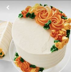 a white cake with orange and yellow flowers on it next to a slice of bread