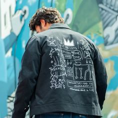 Let Your Creative Side Out This trendy jacket is ideal for art lovers and streetwear aficionados alike, as it was inspired by the work of Jean-Michel Basquiat. Whether you're at a private art opening or just window shopping, people will notice you in this unique and eye-catching ensemble. Comfort and Quality Construction Made from high-quality materials, this mechanic's jacket features a comfortable yet long-lasting fabric blend that keeps you warm and dry. A heavy-duty zipper and ribbed cuffs a Urban Style Outerwear With Graphic Print For Urban Adventures, Artistic Winter Streetwear Outerwear, Artistic Winter Outerwear For Streetwear, Artistic Black Outerwear For Fall, Artistic Graffiti Print Outerwear For Streetwear, Artistic Cotton Outerwear With Graphic Print, Artistic Cotton Outerwear For Streetwear, Artistic Black Long Sleeve Outerwear, Mechanics Jacket