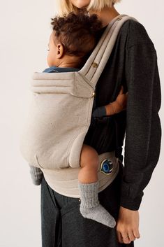 a woman is holding a baby in a sling that's attached to her back