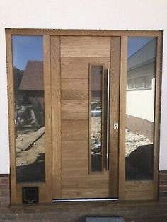 a wooden door with glass and side panels on the front of a house next to a brick wall