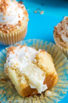 three cupcakes with white frosting and sprinkles on blue paper plates