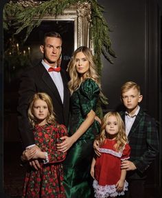 a man and two children standing next to each other in front of a christmas wreath