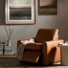 a brown leather chair sitting in front of a painting