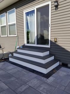 a patio with steps leading up to the front door and windows on the side of the house