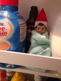 an elf is hiding in the shelf next to some drinks and other things on it