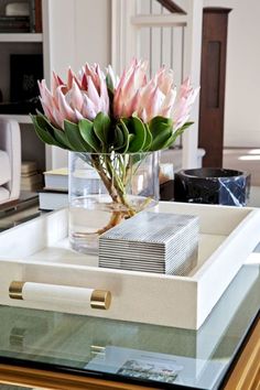 a vase with pink flowers sitting on top of a glass table