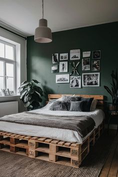 a bed made out of wooden pallets in a room with green walls and pictures on the wall