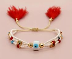 the bracelet is decorated with beads and red tassels on top of white string