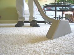 a carpet cleaning company logo with a person using a vacuum to clean the carpet in front of a coffee table