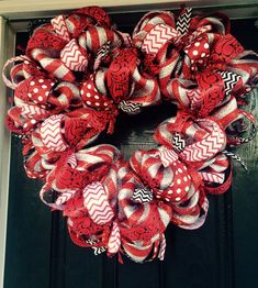 a red and white mesh wreath on a black door with polka dots, chevrons and stripes