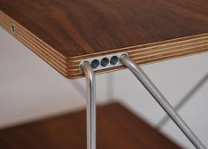 a wooden table with two metal bars on the top and one is bent down to form a triangle