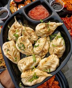 dumplings and sauces are being served in trays