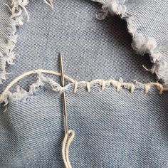 a pair of scissors is cutting through the holes in denim fabric that has been stitched together