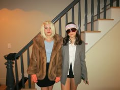 two women standing next to each other in front of stairs