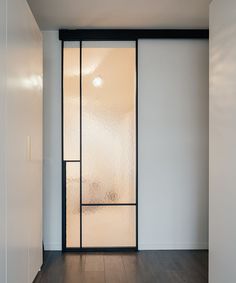 an empty room with a glass door and wood flooring in front of the wall