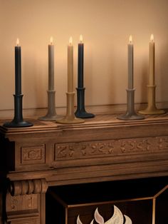 four candles are lit in front of a fireplace with an ornament on the mantle