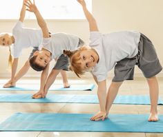 two children are doing yoga on blue mats